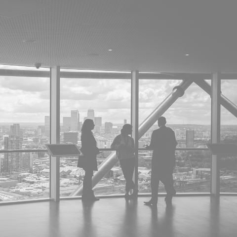 People standing against window overlooking city
